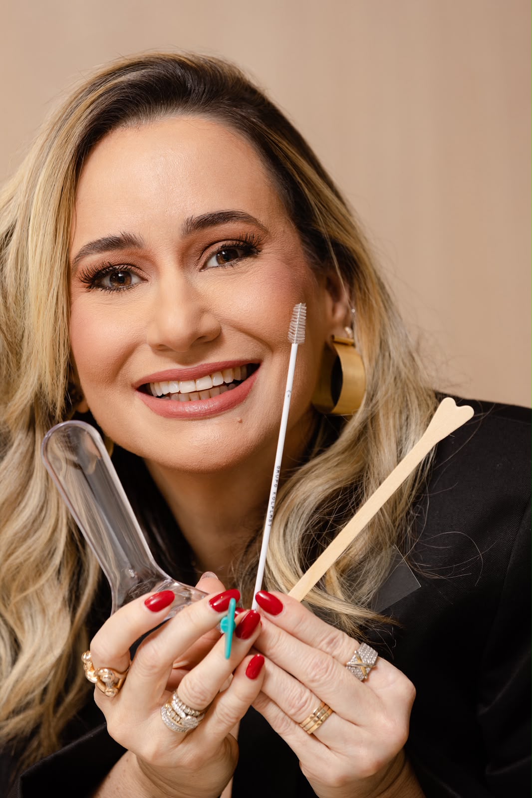 Dra. Thayse Ferro sorrindo e segurando instrumentos de consulta ginecológica